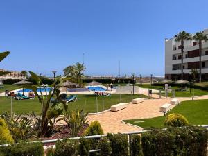 park z ławkami, basen i budynek w obiekcie Terrazas de Campoamor Barbara w mieście Playas de Orihuela