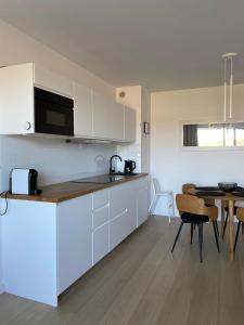 a kitchen with white cabinets and a table with chairs at Apartament Coral in Grzybowo