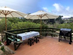 a patio with a table and an umbrella and a grill at Agradable y Acogedora casa de playa in Papudo