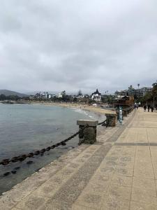 a beach with benches and the water and buildings at Agradable y Acogedora casa de playa in Papudo +9 photos