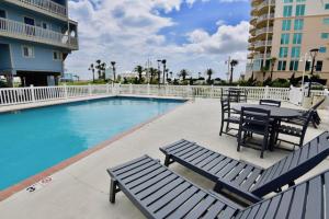 a patio with a table and chairs next to a swimming pool at Summer House West B103 in Gulf Shores