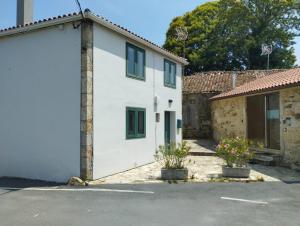 a white house with green windows and a garage at Casa Aldea de Abaixo in Lugo