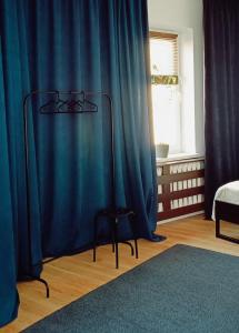 - une chambre avec des rideaux bleus et un tabouret en face d'un lit dans l'établissement Duży prywatny pokój blisko Starego Miasta. Pokój 7, à Varsovie