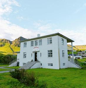a large white building with stairs in a field at Arsalir Guesthouse Vik B&B in Vík