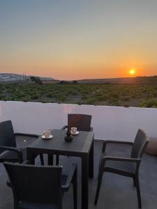 un patio con mesa, sillas y puesta de sol en Zana's Villas-Zenia en Akrotiri