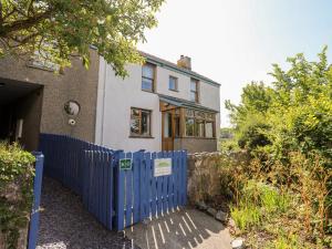 una casa con una valla azul delante de ella en Ynys Faelog Cottage en Menai Bridge