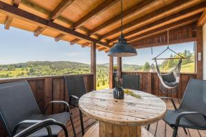 a porch with a wooden table and chairs and a hammock at Domki Zielone Wzgórze 606-819-046 in Polańczyk