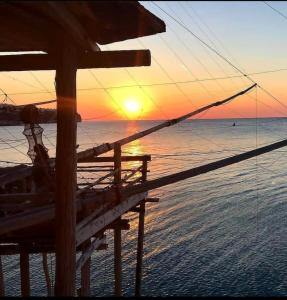 un tramonto sulla spiaggia con il sole che tramonta sull'oceano di Appartamento Grandi a Peschici