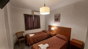 a hotel room with two beds and a lamp at Hotel Caribe in Mar del Plata