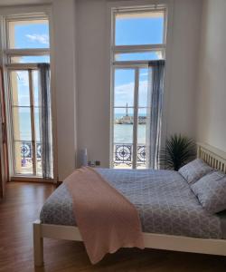 a bedroom with a bed and two large windows at Imperial Suites Heart Of Margate! sleeps 6 in Kent