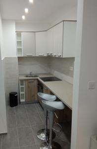una cocina con armarios blancos y taburete. en Apartment Nika Budva, en Budva