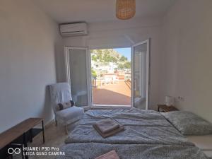 a bedroom with a bed and a chair and a window at Cassa Beata en La colina in Cullera