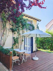 einen Tisch, Stühle und einen Regenschirm auf einer Terrasse in der Unterkunft Comfortable house 20 min to Paris with garden and BBQ in Épinay-sur-Orge