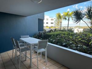 a table and chairs on a balcony with palm trees at Prime Position – Dream Holiday Unit in Caloundra!! in Caloundra