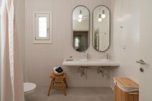 a bathroom with two sinks and two mirrors at Castello Amorgos Suites in Katapola