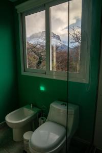 a green bathroom with a toilet and a window at Aizeder - Eco Container in El Chalten