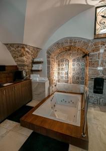 a large bath tub in a room with a stone wall at Templars suite in ‘Akko