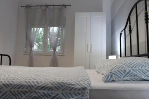 ein weißes Schlafzimmer mit einem Bett und einem Fenster in der Unterkunft FJAKA - Kuća za odmor - NP Krka in Drniš