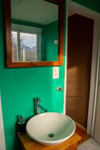 uma casa de banho verde com um lavatório e um espelho em Aizeder - Eco Container em El Chaltén