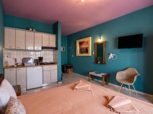 a room with a bed and a kitchen with blue walls at ThassCities Casa Studios in Limenas