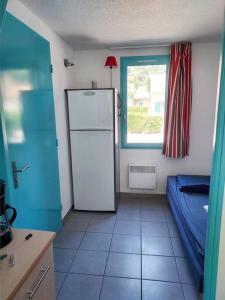 une cuisine avec un réfrigérateur blanc et une fenêtre dans l'établissement Maisonnette Bleue Caraïbe, à Argelès-sur-Mer