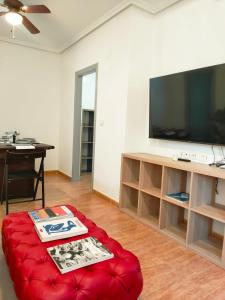 sala de estar con TV grande y reposapiés rojo en Apartamento La Manga Del Mar Menor, en La Manga del Mar Menor