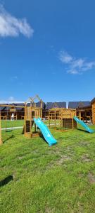 einen Spielplatz mit zwei Rutschen auf einem Grasfeld in der Unterkunft Park Resort Trzęsacz in Trzęsacz