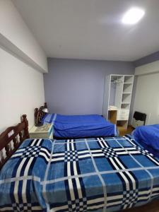 1 dormitorio con 2 camas y edredón azul en hostel comunidad Ushuaia en Ushuaia