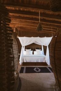 a bedroom with a white bed with a canopy at Playa Viva in Juluchuca