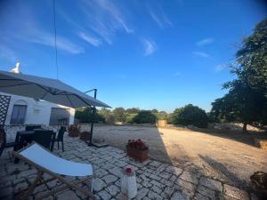a patio with an umbrella and a table and chairs at Masseria Helianthus in Ceglie Messapica