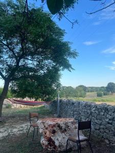 een tafel en stoelen naast een stenen muur bij Masseria Helianthus in Ceglie Messapica