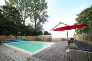 a swimming pool with a red umbrella and a chair at Dolce Villa Pool and Wellness in Francorchamps