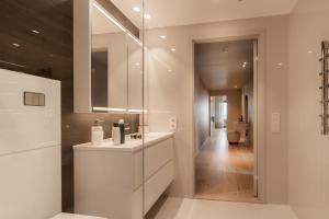 Vindlys Luxury Penthouse Apartment في ترومسو: حمام مع حوض ومرآة