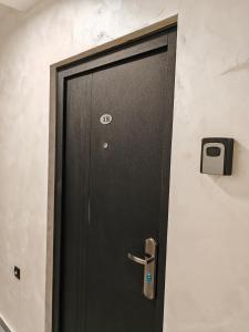 una puerta negra en una habitación con TV en la pared en Apartman Holiday 1, en Veliko Gradiste
