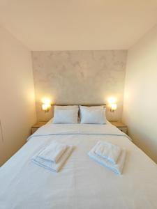 a bedroom with a white bed with two towels on it at Apartman Holiday 1 in Veliko Gradište