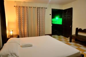 a bedroom with a white bed and a television at Cabina Rainforest , Valle Azul - Near Fortuna Arenal Volcano in San Lorenzo