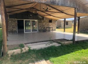 a patio with a stone building with a wooden roof at Finca Lo de Guarin in Vaqueros