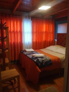 1 dormitorio con 2 camas y cortinas de color naranja en hostal ollantaytambo apartments, en Ollantaytambo