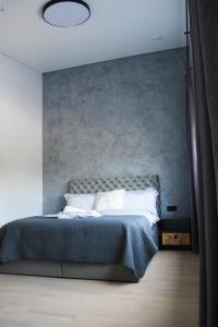 a bedroom with a bed with a gray wall at Koala rest house in Druskininkai