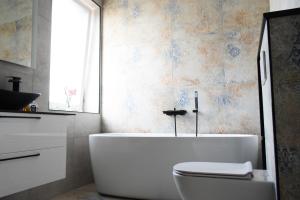 baño con bañera, aseo y ventana en Koala rest house, en Druskininkai
