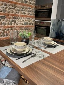 einen Holztisch mit Tellern und Weingläsern darauf in der Unterkunft Appartement climatisé avec balcon et parking privé in Toulouse
