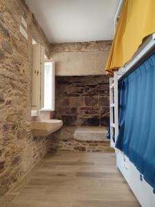 a bathroom with stone walls and a blue curtain at Hostel SP 55 by Bossh! Hotels in Santiago de Compostela