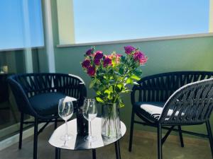 a table with two chairs and a vase of flowers at Arena Prestige Rooms in Pula