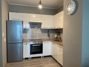 a kitchen with a refrigerator and a clock on the wall at Vetulaniego Canary Comfort Apartment in Kraków