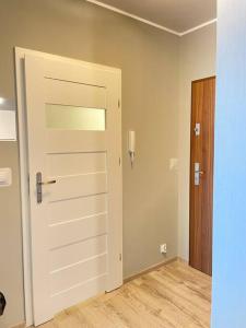 an empty room with a white door and a wooden floor at Vetulaniego Canary Comfort Apartment in Kraków