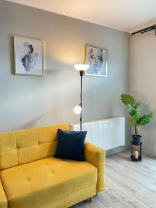 a living room with a yellow couch and a lamp at Vetulaniego Canary Comfort Apartment in Kraków