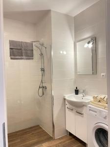 a white bathroom with a shower and a sink at Vetulaniego Canary Comfort Apartment in Kraków