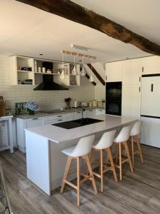 una cocina con armarios blancos y una isla de cocina con taburetes en Casa da Vizcaya, Xilloi beach, en O Vicedo