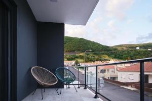2 sillas sentadas en un balcón con vistas en feel... Azores - apartments, en Velas
