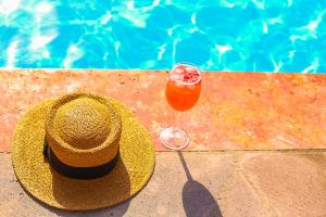 Phoenix Villa في Zarritʼapʼ: قبعة من القش ومشروب بجوار حمام سباحة